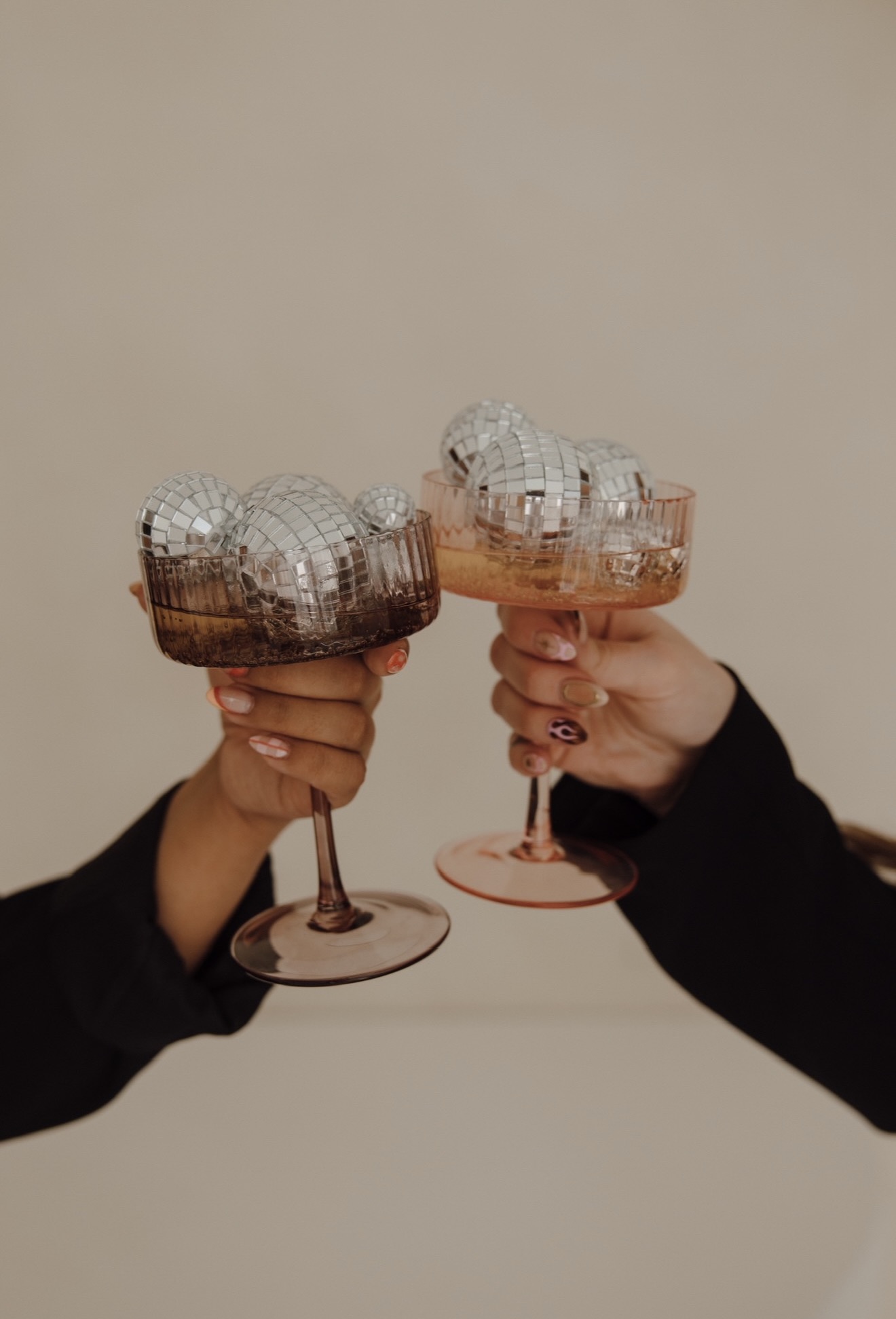 Two elegant champagne coupes toasting with disco ball ornaments